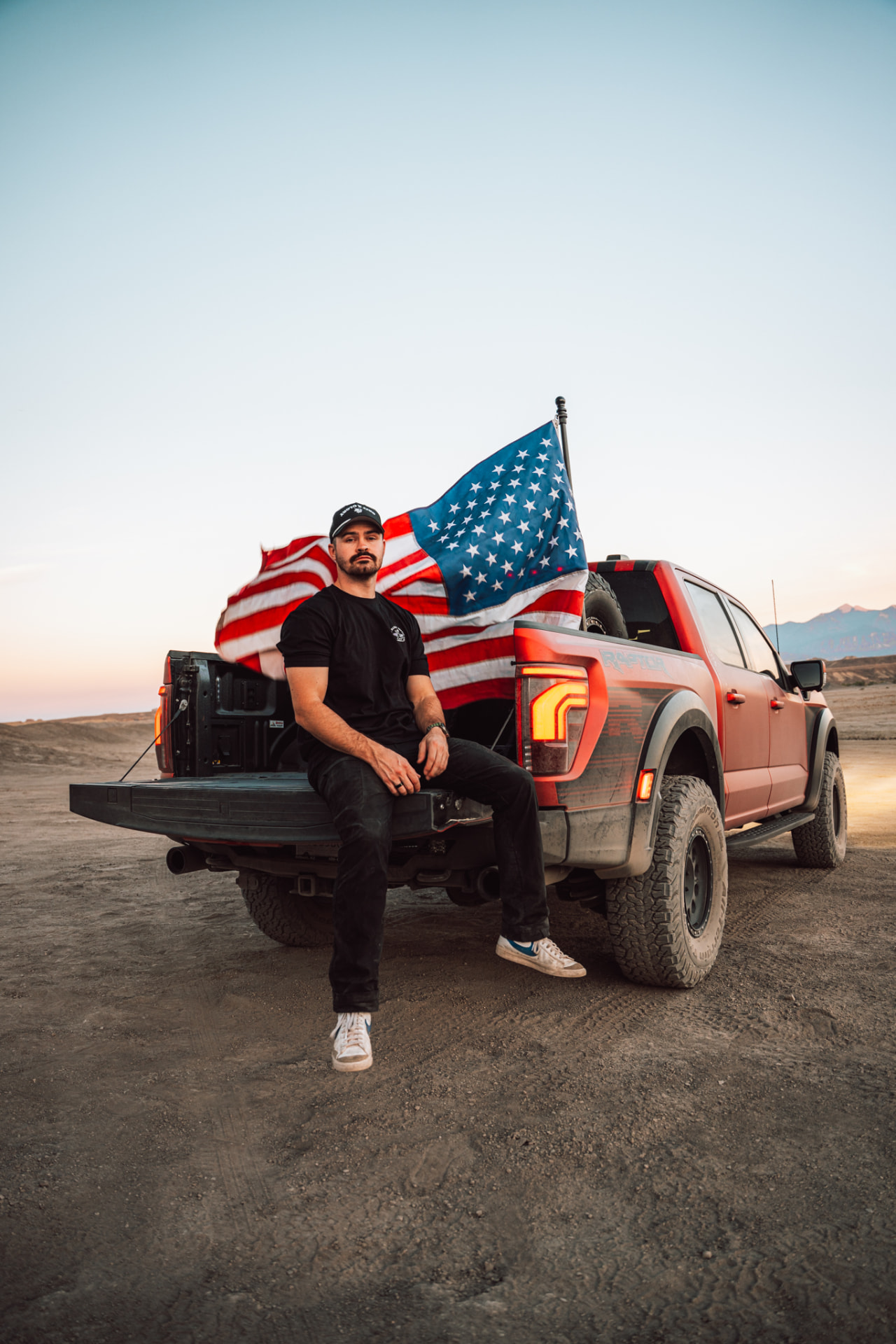 Joshua Rezende seated on the tailgate of a Ford Raptor in the Arizona desert